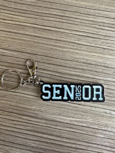 a keychain with the word senior on it is sitting on a table next to a pair of scissors