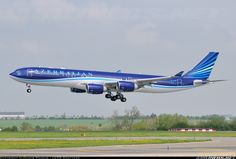 a blue and white airplane taking off from an airport runway with trees in the background