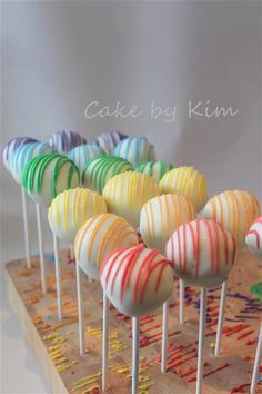 there are many colorful candy lollipops lined up on a wooden tray with the words cake by kim