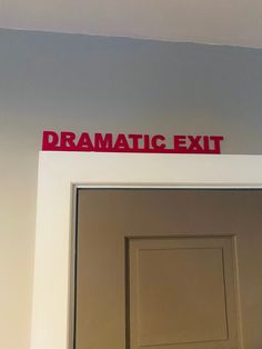 the sign above the door says dramatic exit and is red with black lettering on it