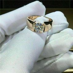 a close up of a person's hand holding a ring with a diamond in it