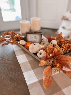 a table topped with candles and pumpkins on top of a checkered table cloth