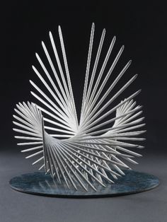 an artistically designed glass sculpture on a blue plate with white lines in the shape of a peacock