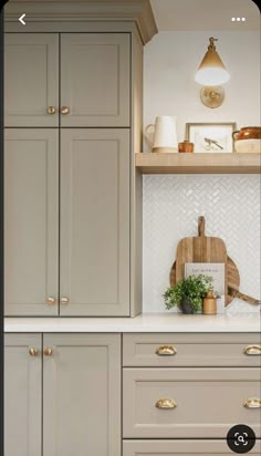 a kitchen with white cabinets and gold handles