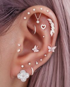 a woman wearing ear piercings with butterflies and hearts on the inside of her ear