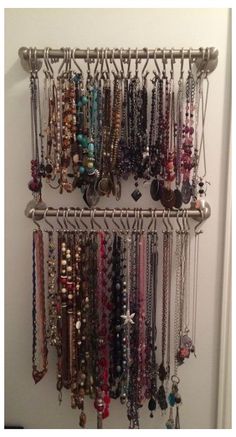 a bunch of necklaces are hanging on a metal rack next to a white door