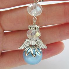 a hand holding a blue beaded necklace with an owl charm