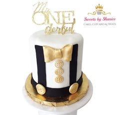 a white and black cake with gold trimmings is decorated with a bow tie