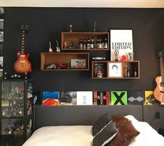 a bedroom with black walls and guitars on the wall