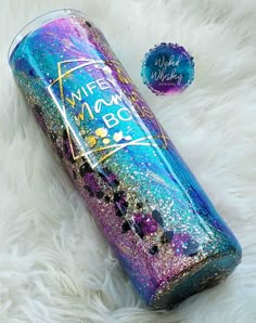 a purple and blue glittered water bottle sitting on top of a white fur covered floor