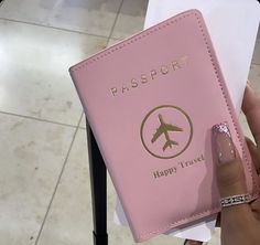 a person holding a pink passport case with a plane on it's front cover