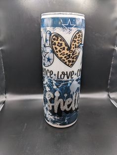 a blue and white coffee cup with a leopard print heart on the side, sitting on a metal surface