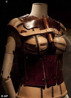 a mannequin is dressed in leather and holds a wooden handle on it's back