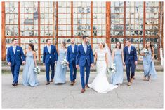 a bride and groom with their bridal party in front of an old rusty building