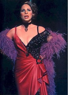 a woman in a red dress with purple feathers on her shoulders and one hand on her hip