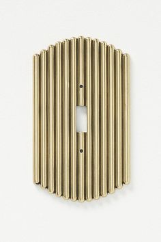 a light switch cover in gold with vertical lines on the back and one single outlet