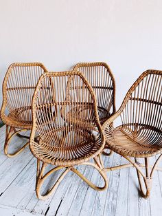 three wicker chairs sitting next to each other on a white wooden floor in front of a wall