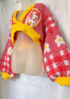 a mannequin wearing a red and yellow sweater with white flowers on the sleeves