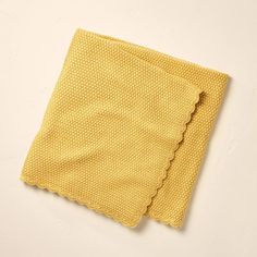 a yellow cloth with scalloped edges on a white surface, folded in half