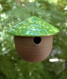 a green bird house hanging from a tree