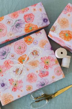 sewing supplies are laid out on a table with scissors, thread and flowers printed wrapping paper