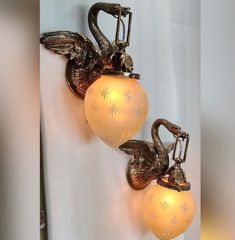 two wall sconces mounted to the side of a white curtain with swans on them