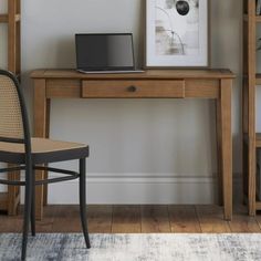 a laptop computer sitting on top of a wooden desk next to a book shelf and chair