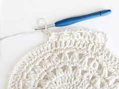 a crocheted white doily with a blue handle