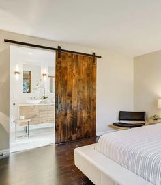 a bedroom with a bed, dresser and sliding glass door that leads to the bathroom