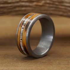 a wedding ring with wood and silver inlays on the inside, sitting on a wooden surface