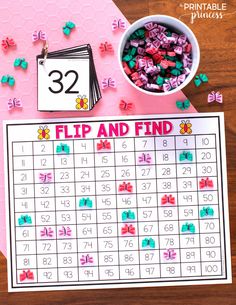 a pink and white calendar with flowers on it next to a cup filled with candy