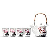 a tea pot and four cups with flowers on them