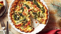 a quiche with spinach and cheese in a pie dish on a wooden table