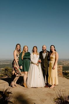 a group of people standing next to each other on top of a hill with mountains in the background