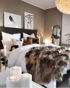 a bedroom with white and brown decor, candles and pictures on the wall