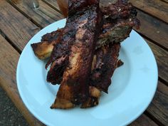 some ribs are on a white plate next to a drink