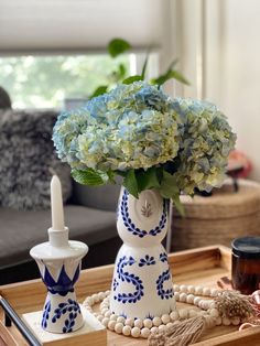 a blue and white vase sitting on top of a wooden tray next to a candle