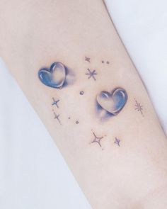 two heart shaped tattoos on the arm and leg, with stars in the sky behind them