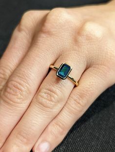 a woman's hand wearing a ring with a square shaped blue stone on it