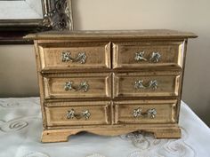 an old dresser with silver knobs on it's drawers sits on a white tablecloth