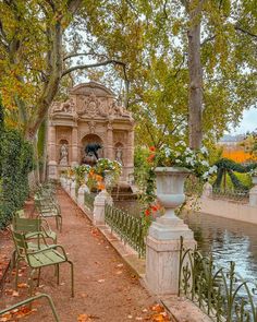 the park is full of benches and tables with flowers on them in front of a fountain