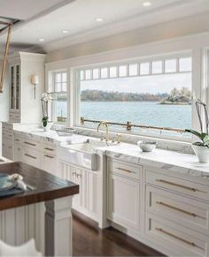 a large kitchen with white cabinets and marble counter tops, along with an ocean view