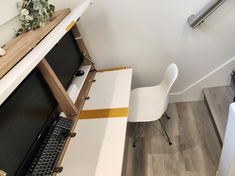 a desk with a keyboard and mouse on top of it next to a wall mounted monitor