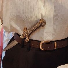 there is a belt that has a knife in the middle of it, on top of a dress shirt