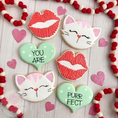 decorated cookies are arranged in the shape of hearts and cats with words written on them