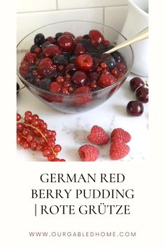 a glass bowl filled with berries next to some raspberries on a counter top