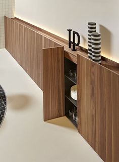 a wooden cabinet with two black and white striped vases on it's shelf