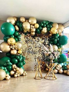 a room filled with lots of green and gold balloons