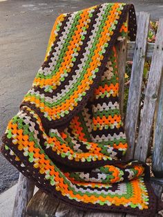 a crocheted blanket sitting on top of a wooden bench