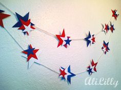 red, white and blue stars are hanging from a string in the corner of a room